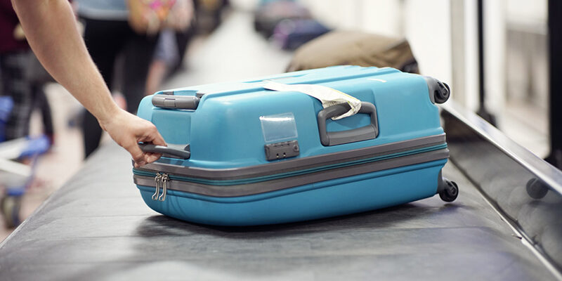 Suitcase on luggage conveyor belt carousel in the baggage claim at airport