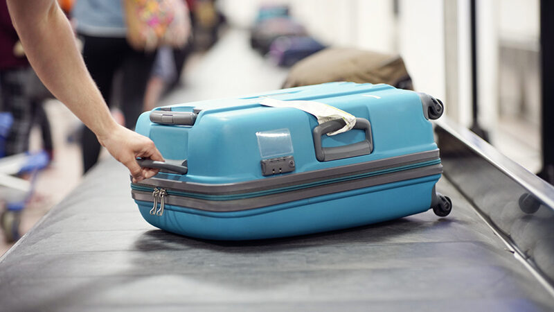 Suitcase on luggage conveyor belt carousel in the baggage claim at airport